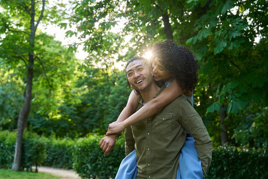 Happy multi ethnic couple piggybacking in green park