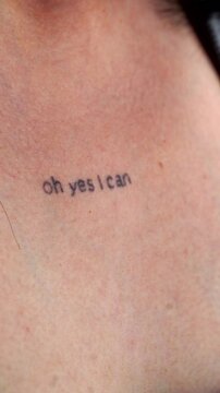 The girl has a tattoo on her body with the inscription OH YES I CAN.
Text on human skin.
Modern girl with a tattoo on her body