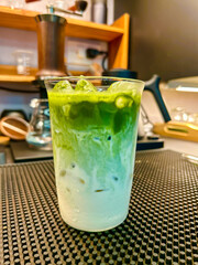 Green tea latte, Japanese iced matcha latte with whipped green tea and milk  on a trendy coffee shop background.