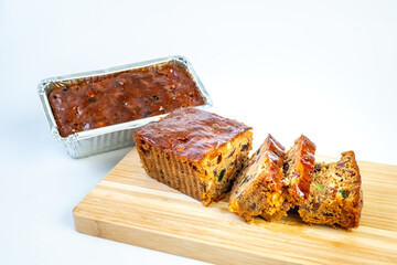 Delicious dried fruit cake sliced on a cutting board isolated on a white background.