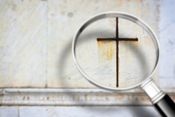 Looking for faith - concept image with a magnifying glass in front of a Christian cross