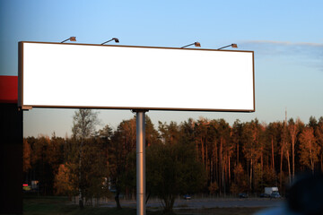 Advertising billboard along the road in the city on a autumn sunny evening. Background for design. 