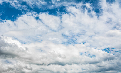 White clouds scattered around a vivid blue sky forming a circular opening that creates a dynamic...