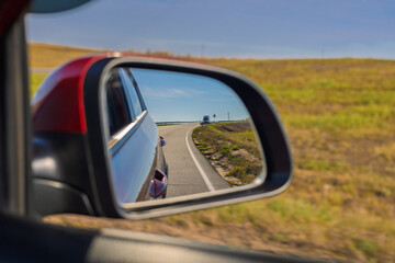 Obraz premium Video shooting in motion, view in the rear view side mirror of a auto, driving a red car along the road