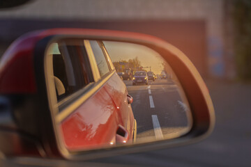 The sun is reflected in the mirror, evening road. View in the rear view side mirror of a auto,...
