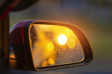 The sun is reflected in the mirror, evening road. View in the rear view side mirror of a auto,...