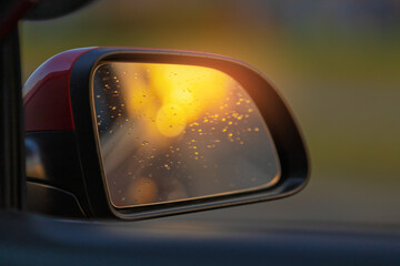 The sun is reflected in the mirror, evening road. View in the rear view side mirror of a auto,...