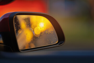 The sun is reflected in the mirror, evening road. View in the rear view side mirror of a auto,...