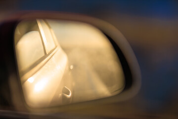 The sun is reflected in the mirror, evening road. View in the rear view side mirror of a auto,...
