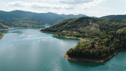 Obraz premium Stunning aerial view of forested peninsula surrounded by blue waters of Zaovine Lake in springtime Serbia. Tara National Park
