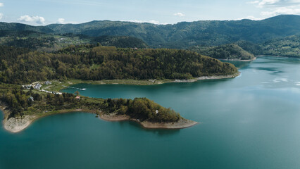 Aerial view panorama of tranquil blue Zaovine Lake with forested slopes and scattered homes in Tara...