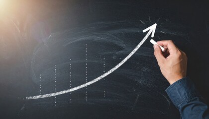 Hand drawing a growth arrow on a chalkboard representing business success and financial increase with a chalk and dark background