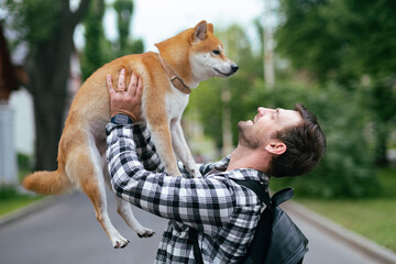Young man in plaid shirt walking with shiba inu dog in summer park sunny day joyful outdoor activity pet companionship concept lifestyle