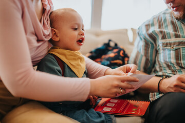 A joyful moment of a child interacting with parents during a family book reading time at home,...