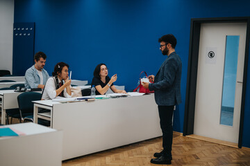 A professor assists a diverse group of students during a class. The classroom setting fosters an...
