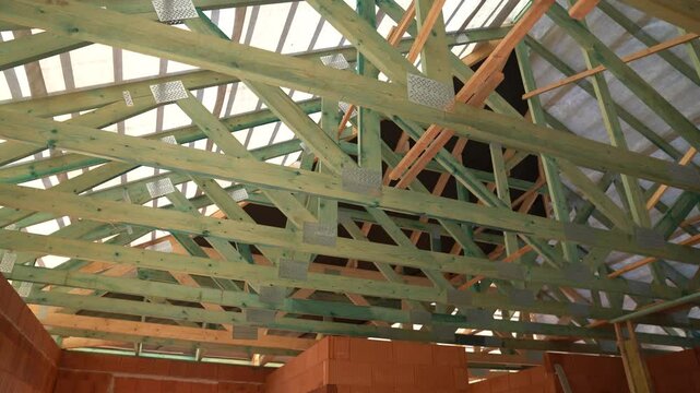 Wooden roof trusses and beams installed on new house under construction