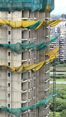 High-rise building under construction with safety nets draped along the floors for worker...