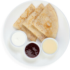 Three thin pancakes on a white plate with three sauces stacked in a triangle on a white background