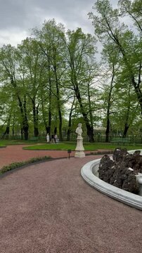 Review vertical video of Crown Fountain of Summer Garden of St. Petersburg, created by architect M. Zemtsov in 1725 and sculptural busts surrounding it on rainy May day
