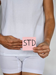 Woman holds in pot and paper with STD inscription. Female person feels symptoms and pain due to...