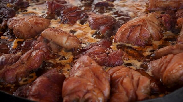 Close-up footage of delicious fried pork trotters, a classic German or Czech dish that is cooked bubbling in a cauldron. Popular street fair food. Appetizing pork trotters