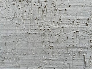 rough white stucco wall with weathered pitted texture and subtle vertical drip patterns ideal for grunge graphic design, urban backdrop, or abstract branding element

