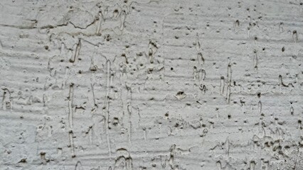 rough white stucco wall with weathered pitted texture and subtle vertical drip patterns ideal for grunge graphic design, urban backdrop, or abstract branding element

