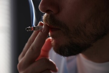 Man smoking cigarette on blurred background, closeup