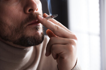 Man smoking cigarette on blurred background, closeup