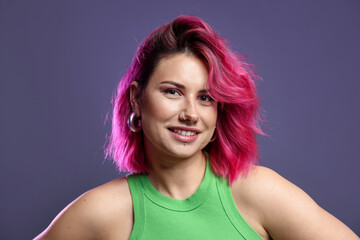 Beautiful woman with pink dyed hair on violet background
