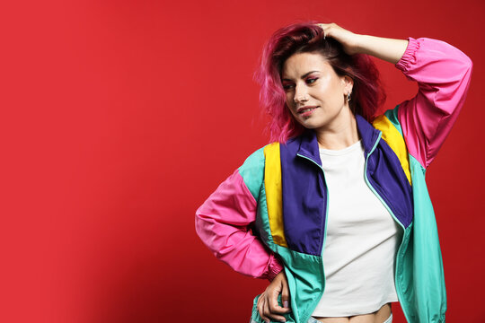 Fototapeta Beautiful woman with pink dyed hair on red background, space for text