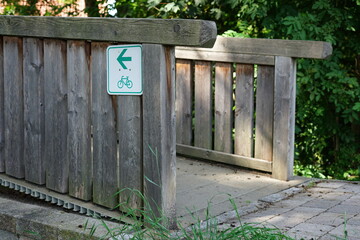 A wooden bridge with a green bicycle route sign featuring a directional arrow. 