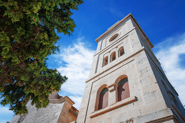 Church of St. George in Primosten, Croatia, featuring a historic stone bell tower with a clock and...