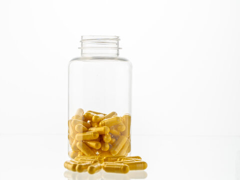 A jar of pills inside and scattered pills on a white background. Hyaluronic acid, collagen, vitamins or barberry pills to maintain beauty and lose weight. Copyspace