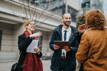 Businesspeople engaging in a collaborative conversation outside an office building, showcasing teamwork and professional interaction in a relaxed environment