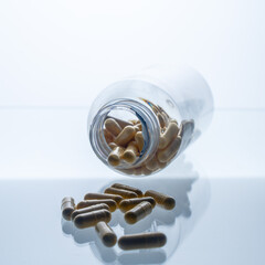A jar with pills inside lies on a white background with reflection. Hyaluronic acid, collagen,...