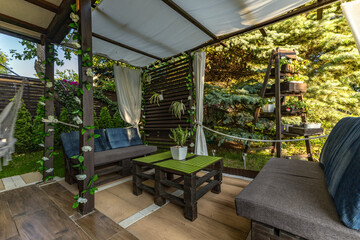 Construction of a wooden garden gazebo, a wooden pergola with white curtains, a relaxation area...