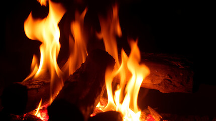 Burning logs with bright orange flames and glowing embers in dark