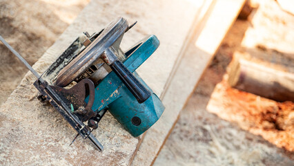 Electric circular saw on timber stack in a wood workshop. Work tool for carpentry used for cutting wooden plank or board. Lumber industry concept