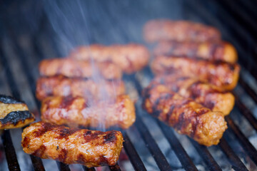 (Mici), traditional Romanian meat dishes on a grill during the cooking