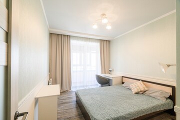cozy bedroom with a bed, desk, curtains, and soft lighting. The room has a simple, calming aesthetic