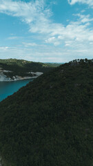 Obraz premium Dense green forest and hilly terrain above Rovni Lake, captured from a drone in western Serbia. Vertical aerial view