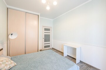 bright, clean bedroom with light blue walls, a bed with a blue blanket, a sliding door closet, and...