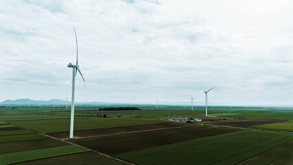Aerial view of wind turbines on vast green fields in Vojvodina, Serbia, during springtime, with...