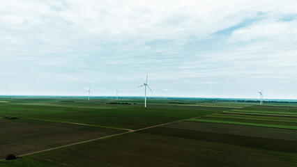 Aerial view of wind turbines on vast green fields in Vojvodina, Serbia, during springtime, with...