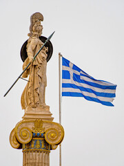 Marble statue of Athena, the Greek Goddess of wisdom and science, on an Ionic column beside the Greek flag in Athens, Greece. Space for your text and logo.