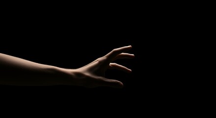 Reaching Human Hand Emerging From Dark Space in Dramatic Lighting