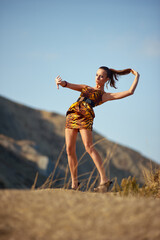 Fashionable woman posing dynamically in nature, showcasing her bold style holding her long hair....