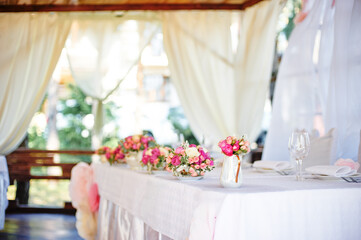 Elegant Wedding Table Decorated With Floral Arrangements and Soft White Curtains