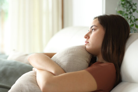 Apathetic woman hugging pillow on a sofa at home